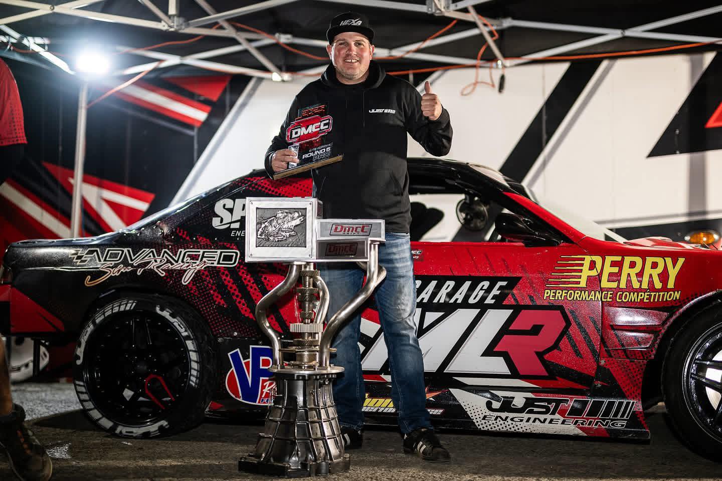 Marc Landreville standing with a DMCC trophy beside the MLR drift car